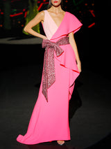 Vestido de fiesta largo realizado en crepe coral y nude, cuerpo escote pico cruzado con volante en un lado, falda de capa cruzada con maxi cinturón de lentejuelas mate granate de Hannibal Laguna.