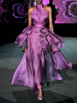 Vestido largo de fiesta realizado en organza de seda color morado. Destaca el elegante juego de plisados que envuelve el cuerpo, creando el elegante cuello halter del diseño. El contrapunto perfecto a la voluminosa falda del vestido, que aporta dinamismo y movimiento de Hannibal Laguna