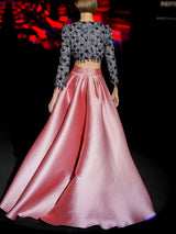 Crop top de fiesta en pedreria de microperlas con malla de lentejuelas azul noche, mangas rectas largas y escote a caja. Falda de fiesta en mikado pique color rosa loto con forma de capa cruzada y abertura de HANNIBAL LAGUNA.