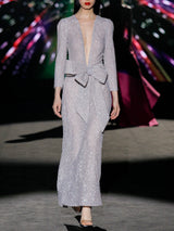 Vestido de fiestaen lentejuelas plata mate, cuerpo escote V con mangas largas y falda sirena entallada. Lazo a modo de cinturón de HANNIBAL LAGUNA.