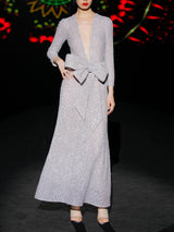 Vestido de fiestaen lentejuelas plata mate, cuerpo escote V con mangas largas y falda sirena entallada. Lazo a modo de cinturón de HANNIBAL LAGUNA.