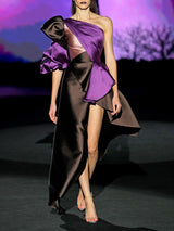 Vestido de fiesta realizado en mikado color chocolate y morado con escote asimétrico drapeado, maxi manga abullonada en dos colores y falda de vuelo con capote bicolor de Hannibal Laguna