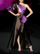 Vestido de fiesta realizado en mikado color chocolate y morado con escote asimétrico drapeado, maxi manga abullonada en dos colores y falda de vuelo con capote bicolor de Hannibal Laguna