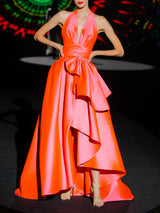 Vestido de fiesta en mikado color salmón, escote pico tipo halter y falda de capa con abertura cruzada y capote de adorno de HANNIBAL LAGUNA.