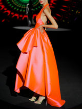 Vestido de fiesta en mikado color salmón, escote pico tipo halter y falda de capa con abertura cruzada y capote de adorno de HANNIBAL LAGUNA.