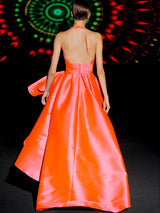 Vestido de fiesta en mikado color salmón, escote pico tipo halter y falda de capa con abertura cruzada y capote de adorno de HANNIBAL LAGUNA.