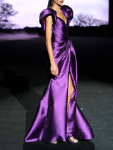 Vestido de fiesta realizado en mikado morado con escote corazón cruzado drapeado, maxi mangas y falda de vuelo cruzada con pliegues de Hannibal Laguna