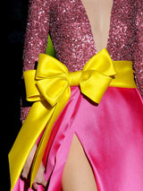 Vestido de fiesta largo en mikado pique fresa y lentejuelas granate, t-shirt con escote V con manga larga y amplia falda de capa cruzada. Cinturón lazo en color lima de HANNIBAL LAGUNA.