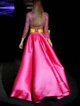 Vestido de fiesta largo en mikado pique fresa y lentejuelas granate, t-shirt con escote V con manga larga y amplia falda de capa cruzada. Cinturón lazo en color lima de HANNIBAL LAGUNA.