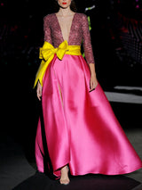 Vestido de fiesta largo en mikado pique fresa y lentejuelas granate, t-shirt con escote V con manga larga y amplia falda de capa cruzada. Cinturón lazo en color lima de HANNIBAL LAGUNA.