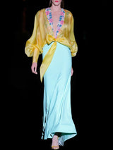 a man in a yellow dress is holding a flower