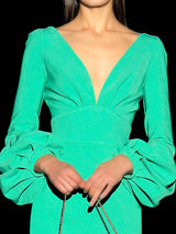 a woman in a green dress holding a wii remote