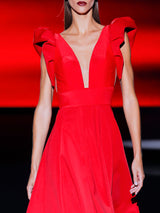 Vestido en neopreno ecológico rojo con falda de nesgas y cuerpo con escote V y mangas XXL de Hannibal Laguna