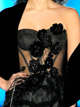 a woman in a black dress holding a black cat