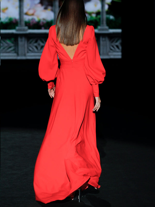 Vestido de noche realizado en satín color geranio con escote en V, destaca el drapeado del cuerpo con pliegues, mangas XL y falda evasé de Hannibal Laguna